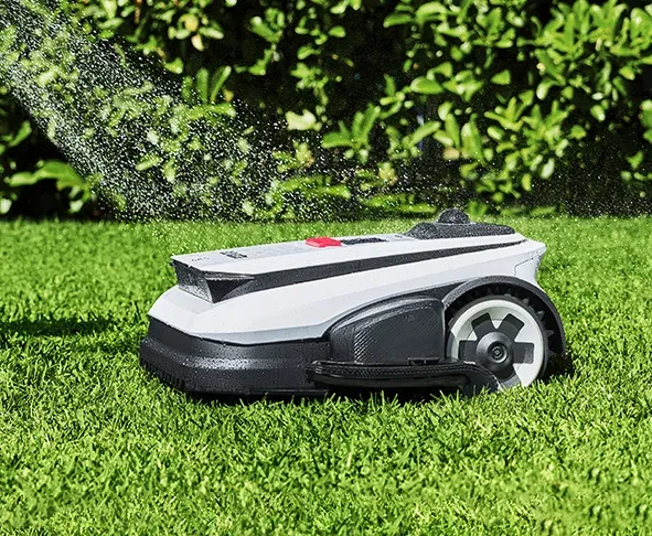 Le robot tondeuse Ecovacs GOAT A1600 LiDAR PRO de profil sur une pelouse, capot blanc et coupe-bordures noir sur la roue avant